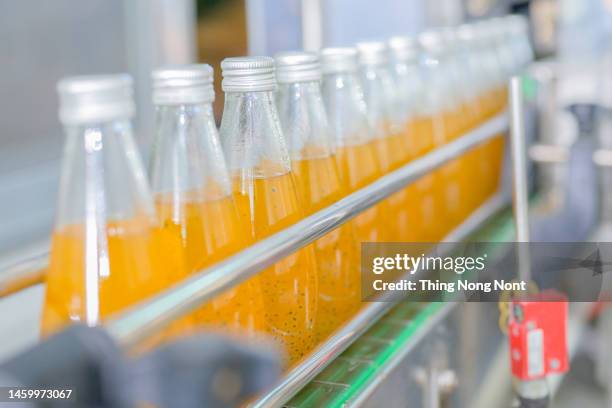 conveyor belt, juice in bottles, beverage factory interior in blue color, industrial production line. - bottling plant stock pictures, royalty-free photos & images