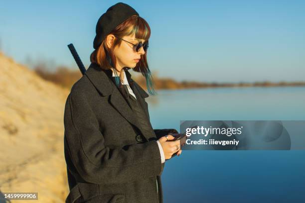 redhead girl in black clothes outdoors. gothic style - black coat stockfoto's en -beelden