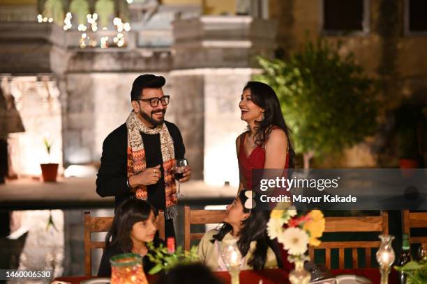 picture of a smiling mature couple with their daughters at an outdoor dinner party - rajasthani dress stock pictures, royalty-free photos & images