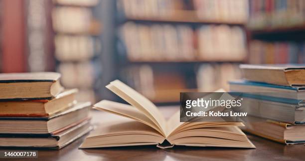library, books on table and background for studying, learning and research in education, school or college. reading, philosophy and open, vintage or history print book, university blurred background - boek stockfoto's en -beelden