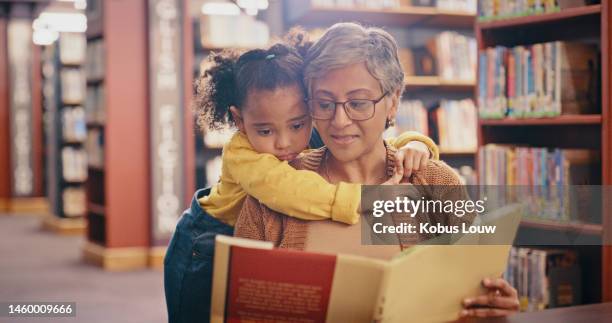 lectura, educación y abuela con nieto en la biblioteca, abrazarse y vincularse mientras están sentados juntos. aprender, contar cuentos y abuela enseñando a la niña, relajarse y disfrutar de los libros, cuentos y desarrollo infantil - nieto fotografías e imágenes de stock