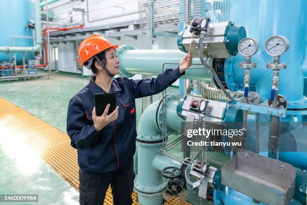 an asian female engineer uses a tablet computer to record equipment in a chemical plant - working oil pumps stock pictures, royalty-free photos & images