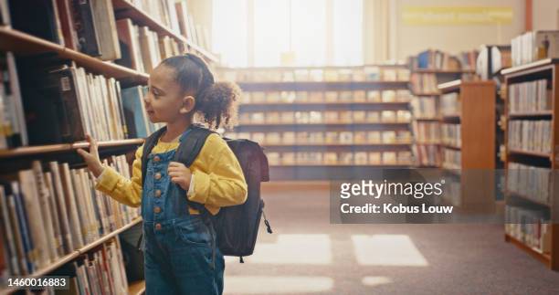 young girl in library, book choice and reading for knowledge, education and learning for school. study, kindergarten student and female kid search bookshelf for story, academic development and growth - contar histórias imagens e fotografias de stock