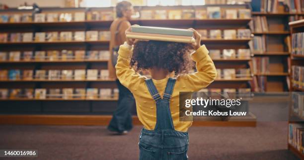 little girl, library and carrying books on head walking to bookshelf from reading finished at the store. female child, kid or toddler done, completed or over with story book time at the shop - verhaal stockfoto's en -beelden