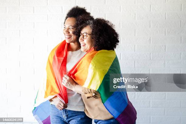 lesbian women covered with a rainbow flag - pride month stock pictures, royalty-free photos & images