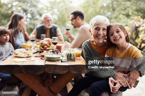 glückliche großmutter und enkelin beim mittagessen der familie auf einer terrasse. - sitting at table looking at camera stock-fotos und bilder