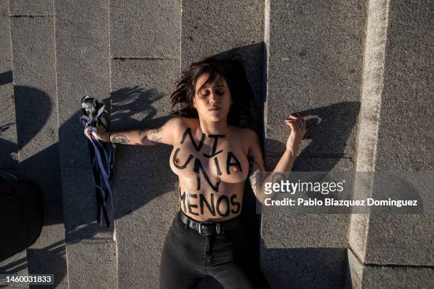 Activist with body paint reading 'Not one less' lays on the ground during a performance as she protest against domestic violence held at El Retiro...