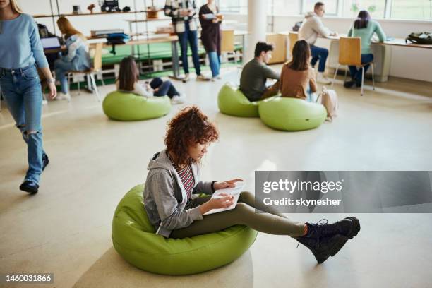 black female student taking notes at campus. - bean bag stock pictures, royalty-free photos & images