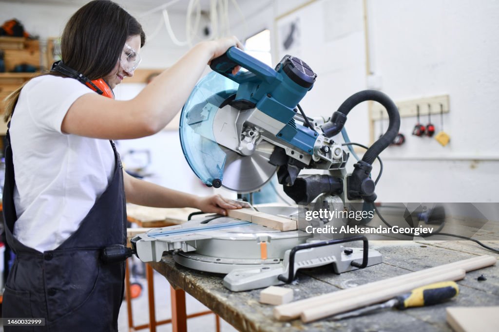 Female Carpenter Expertly Cutting Piece Of Wood