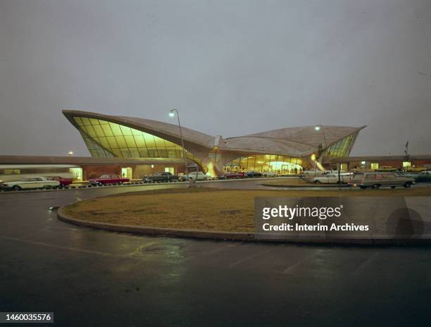Nighttime view of cars parked outside of the Trans World Flight Center at John F Kennedy International Airport, New York, circa 1960. It was designed...