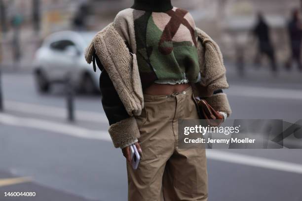 Fashion week guest seen wearing beige wide leg pants, a cropped patterned sweater, a fur leather jacket, dark green shades and a brown leather jacket...