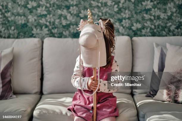 little girl hides behind a toy unicorn - riding unicorn stock pictures, royalty-free photos & images