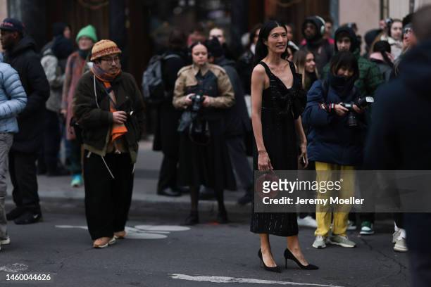 Fashion week guest seen wearing a long black sparkling dress with a big ribbon, black high heels and a brown leather bag before the Viktor & Rolf...
