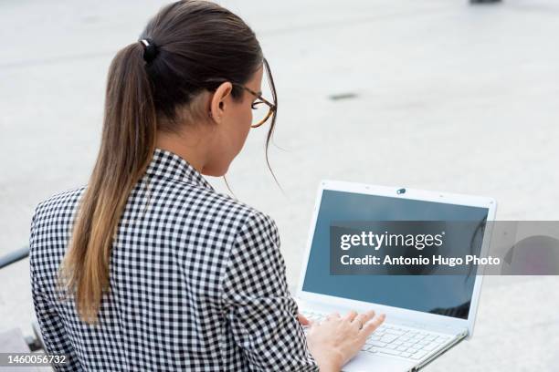 rear view of a young brunette business girl with red lipstick and glasses working on her laptop. business and technology concept. - woman lipstick rearview stock pictures, royalty-free photos & images