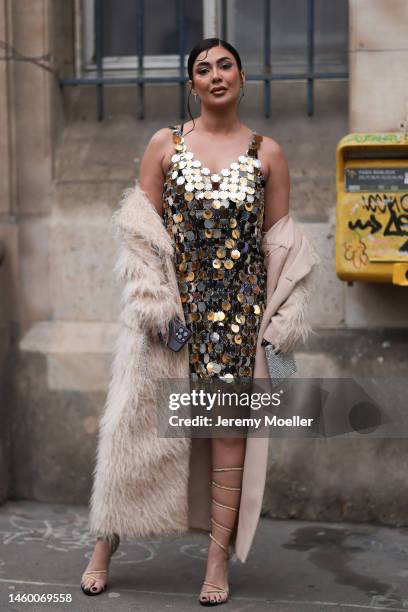 Zena Louay seen wearing a golden sequin dress, a beige fringe coat and high heels before the Elie Saab show on January 25, 2023 in Paris, France.