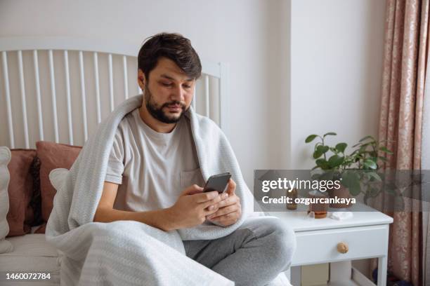kranker mann mit grippe spricht mit einem virtuellen arzt - krankenbett stock-fotos und bilder