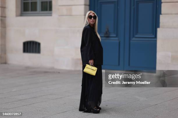 Corina Mihaila Larpin seen wearing black Peter Do jacket, yellow Hermes bag, black Yves Saint Laurent shoes, silver Stefere jewelry, black Linda...