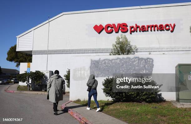 Pedestrians walk by a CVS Pharmacy on January 27, 2023 in Half Moon Bay, California. CVS has announced plans to shorten pharmacy hours in March at...