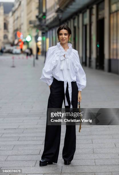 Katie Giorgadze wears white ruffled blouse, black high waisted pants, Valentino bag, platform shoes outside Patou at La Samaritaine on January 27,...