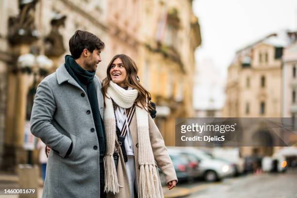 cheerful young couple walking on city street on a winter day. - prague people stock pictures, royalty-free photos & images