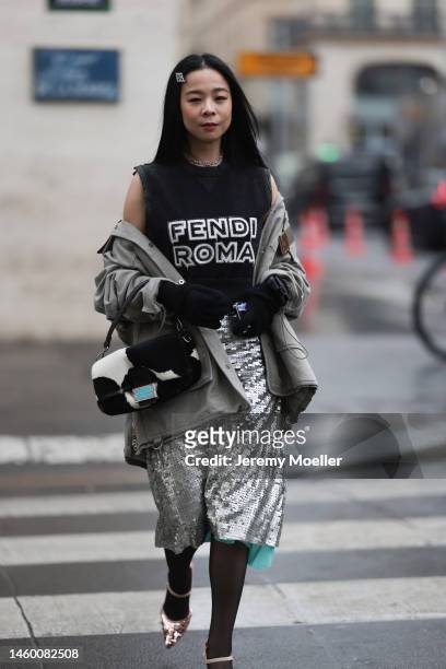 Fashion week guest seen wearing a Fendi look with a Fendi x Tiffany&Co baguette, silver sparkling sequin pants, high heels, a grey coat and a black...