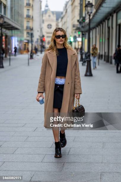 Chloe Lecareux wears cropped knit, boxer shorts, skirt, brown wool coat, black Bottega Veneta bag outside Patou at La Samaritaine on January 27, 2023...