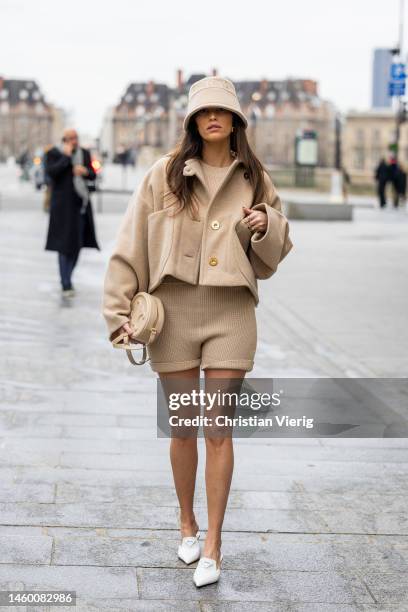 Alison Toby wears beige bucket hat with logo print, button up jacket, shorts, Celine bag, white pointed Prada heels outside Patou at La Samaritaine...