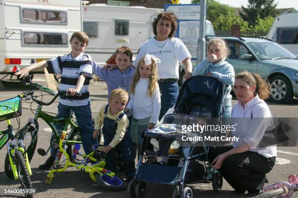 Travellers pose for a photograph in front of caravans belonging to Gypsies who have set up an illegal camp in a car park in Pershore on May 01, 2005...