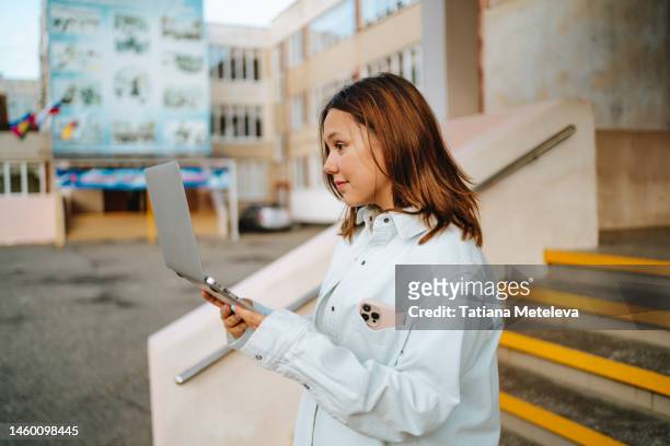 video call and teen social issues. student girl working on a laptop near building staircase outdoors - learning interface video button stock pictures, royalty-free photos & images