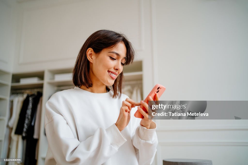 Saleswoman making orders using phone, working in design department of clothes store