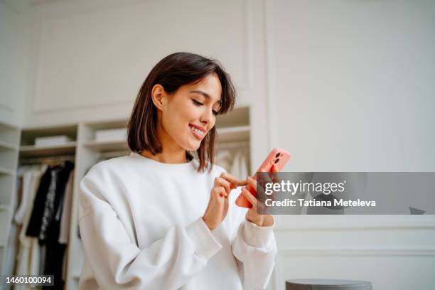 saleswoman making orders using phone, working in design department of clothes store - looking phone stock pictures, royalty-free photos & images