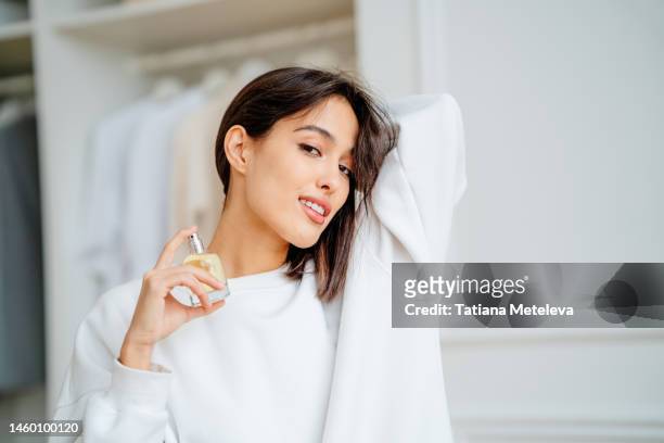 toothy smiling woman spraying and testing perfume oil water on her neck - choosing perfume stock pictures, royalty-free photos & images