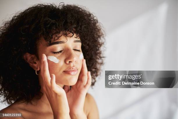 crème, hydratant et visage femme noire dans la promotion des soins de la peau, de la beauté ou des cosmétiques sur fond mural blanc. visage, calme et génération z personnes ou modèle lotion, crème solaire ou hydratant pour les soins de la peau - woman face cleaning photos et images de collection