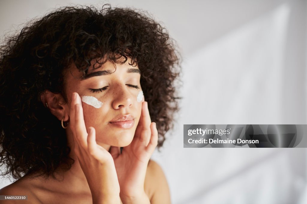Cream, moisturizer and facial black woman in skincare, beauty or cosmetics promotion on white wall background. Face, calm and gen z people or model lotion, suncream or moisturizer for skin care