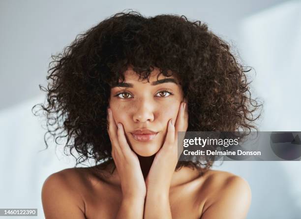 retrato, beleza e facial com uma mulher negra em estúdio para promover cuidados ou tratamentos naturais da pele. rosto, pele e bem-estar com uma jovem atraente tocando suas bochechas para dermatologia - face humana - fotografias e filmes do acervo