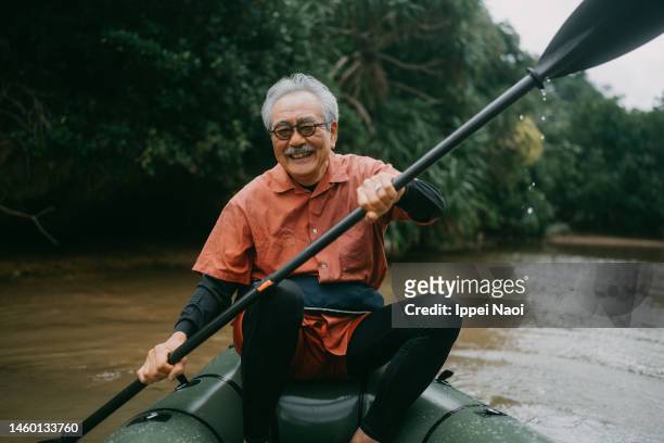 happy senior man enjoying kayaking through mangrove river - okinawa prefecture fotografías e imágenes de stock