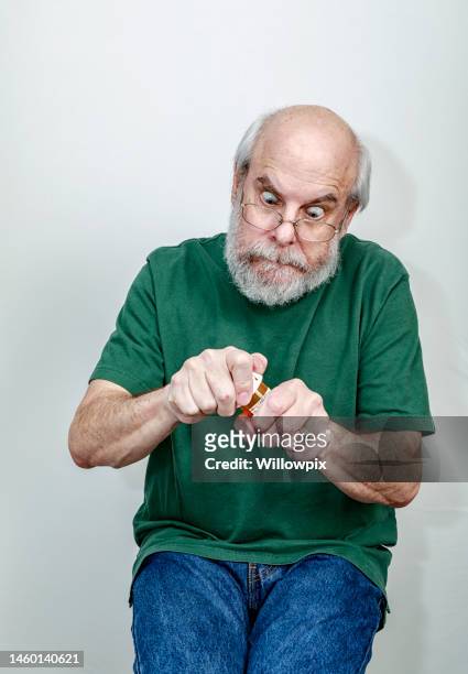 frantic senior man trying to open prescription medicine bottle - high sticking stock pictures, royalty-free photos & images