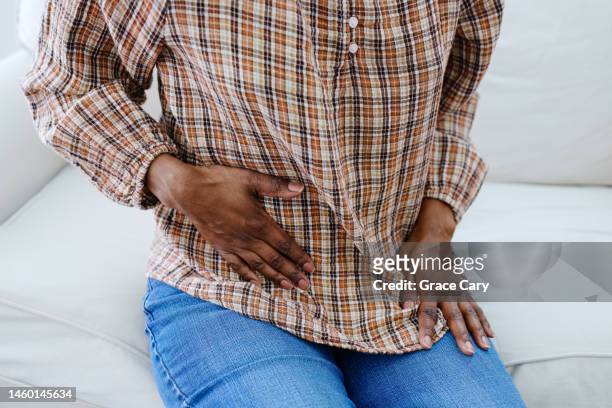 woman holds her abdomen in pain - fibroids stockfoto's en -beelden