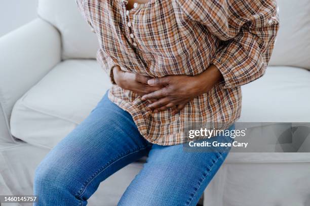 woman holds her abdomen in pain - buikpijn stockfoto's en -beelden