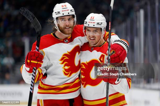 Noah Hanifin and Mikael Backlund of the Calgary Flames celebrate a goal by Hanifin during the third period against the Seattle Kraken at Climate...