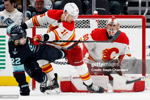 Oliver Bjorkstrand of the Seattle Kraken gets a stick on the puck in front of Nikita Zadorov and Dan Vladar of the Calgary Flames during the third...