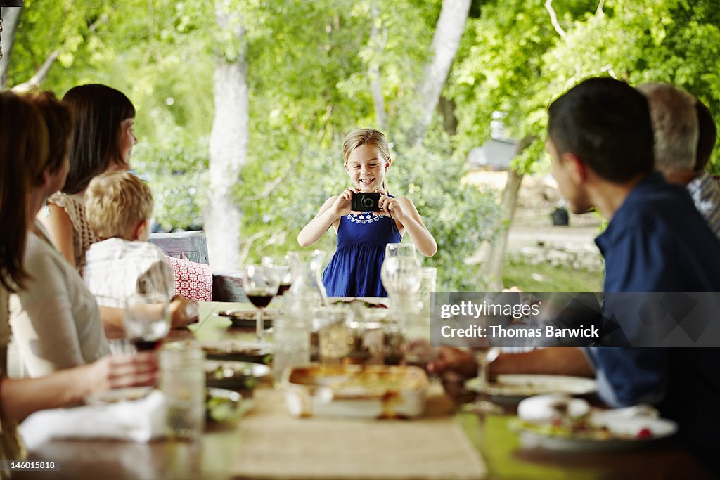 Girl taking photo of family seated for meal