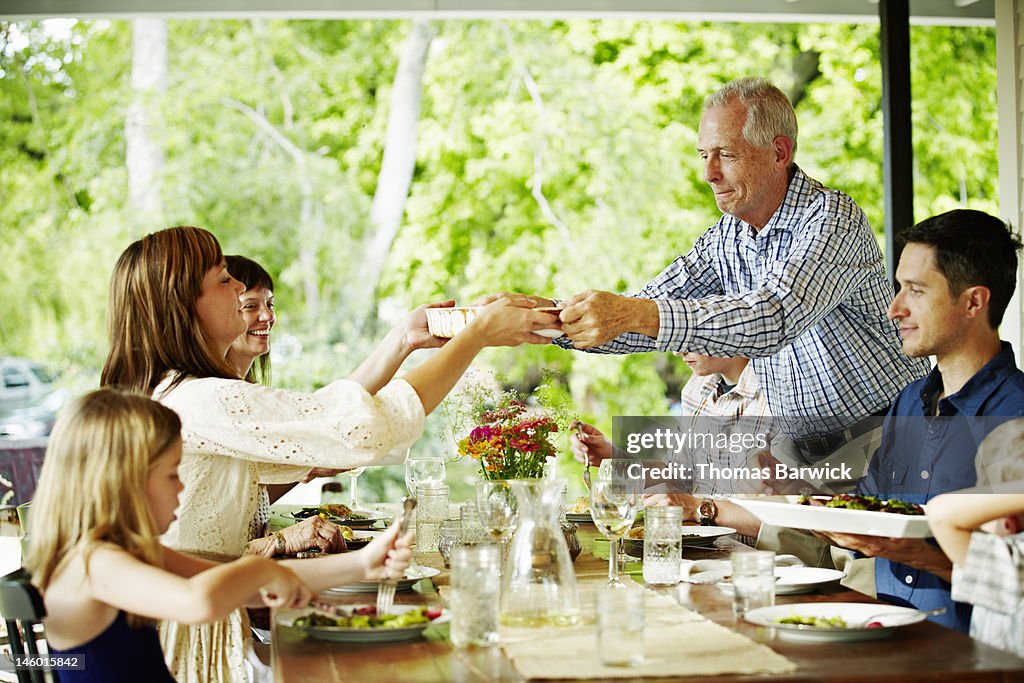 Father handing plate of food across table
