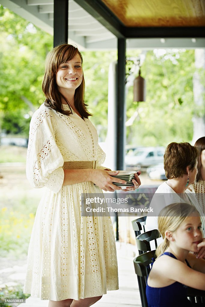 Woman smiling standing holding stack of plates