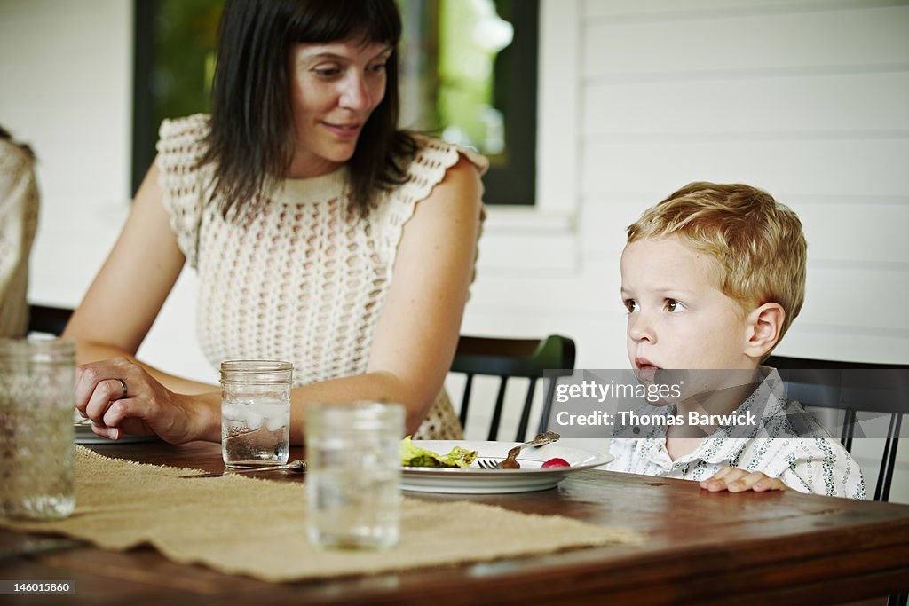 Mother sitting next to son at table outdoors