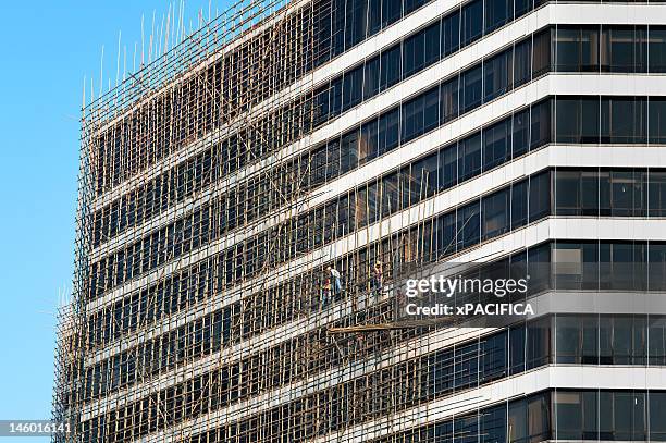 constructions workers on bamboo scaffolding - bamboo scaffolding stock pictures, royalty-free photos & images
