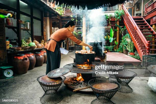 young vietnamese woman cooking steamed fish on open fire in restaurant - vietnam stockfoto's en -beelden