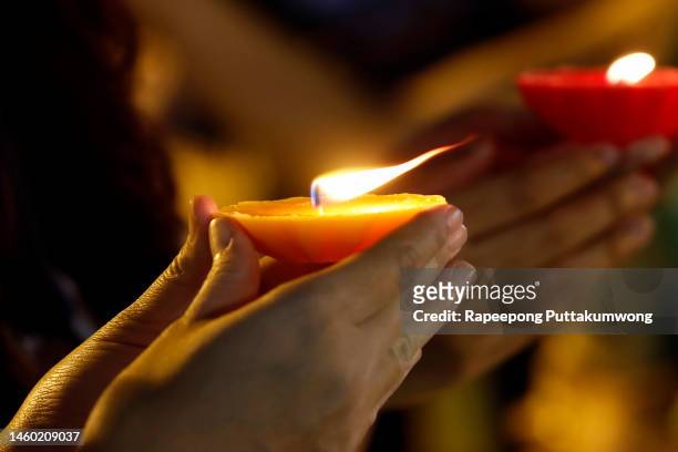 a closeup shot of a woman hands holding candle in hand - buddhism stock pictures, royalty-free photos & images