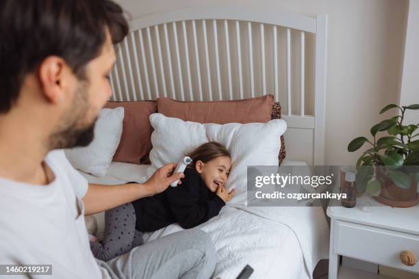 father measuring temperature of her girl with infrared thermometer at home - thermometer turkey stock pictures, royalty-free photos & images