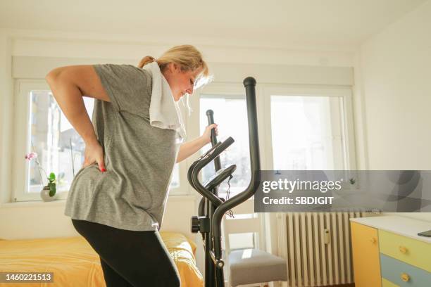 caucasian woman with a backache, exercise on a ski exercise machine - neuropathy stockfoto's en -beelden